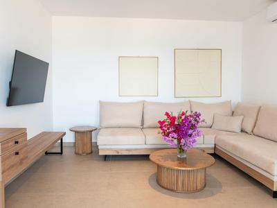 Heller Wohnraum mit beige Ecksofa, rundem Holztisch, Wand-TV und zwei leeren Rahmen.