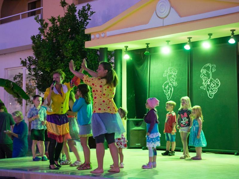 Dzieci bawią się i tańczą na jasno oświetlonej zewnętrznej scenie w nocy.