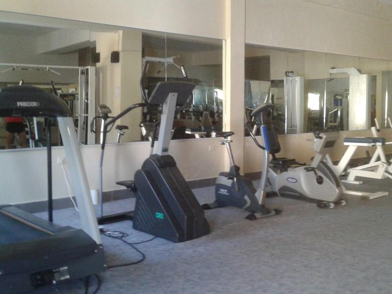 Siłownia z bieżnią, rowerem stacjonarnym i innym sprzętem do ćwiczeń.