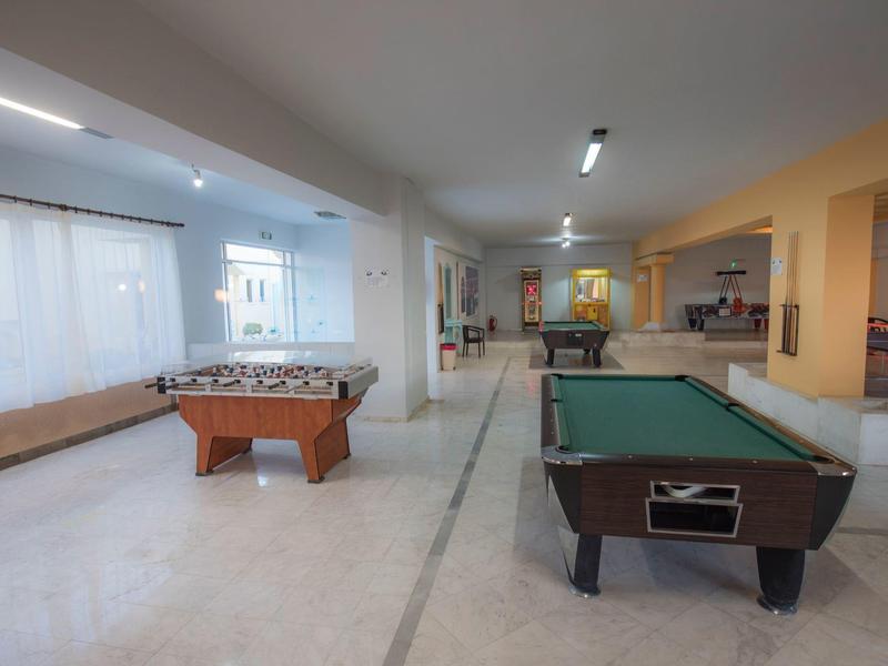 Jasne pomieszczenie rekreacyjne ze stołem bilardowym i piłkarzykami.