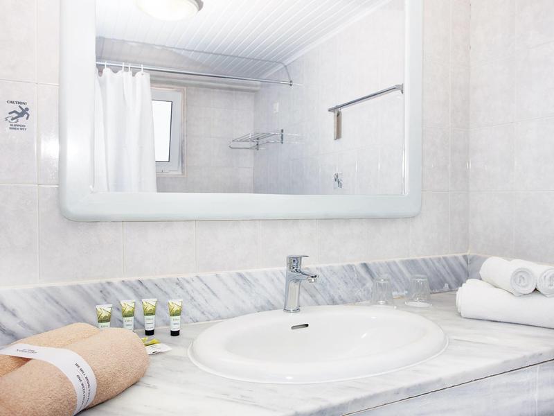 Nowoczesna umywalka w łazience hotelowej z białymi ręcznikami, kosmetykami i lustrem nad nią.