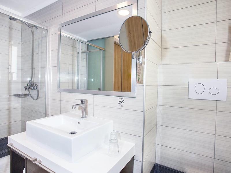 Nowoczesna łazienka hotelowa z białą umywalką, lustrem i szklaną kabiną prysznicową