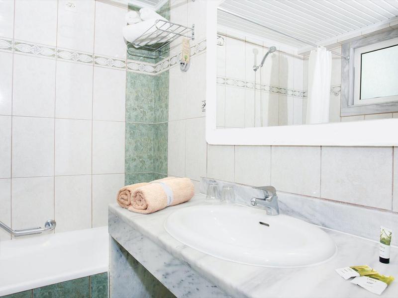 Jasna, czysta łazienka z białymi płytkami, umywalką i wanną.