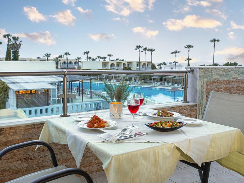 Stolik na zewnątrz z widokiem na basen i palmy o zachodzie słońca.