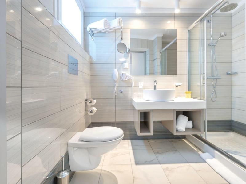 Nowoczesna łazienka z prysznicem, toaletą, umywalką i jasnymi kafelkami.