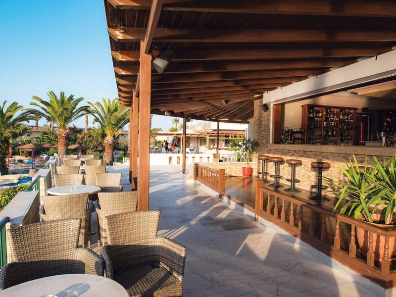 Otwarte bar na plaży z miejscem do siedzenia, drewnianym sufitem i roślinami pod czystym niebem.