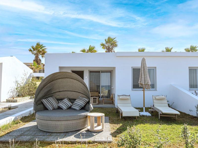 Nowoczesna biała willa z zewnętrznym fotelem i leżakami w słoneczny dzień z palmami