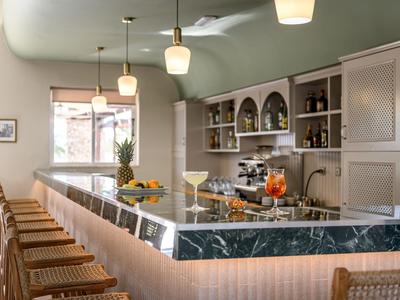 Bar dell'hotel moderno con piano in marmo, sgabelli in legno e illuminazione elegante.