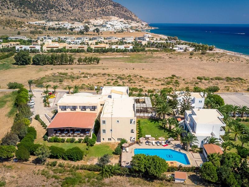 Blick auf ein Landhaus mit Pool, Feldern, Hügeln und dem türkisblauen Meer im Hintergrund.