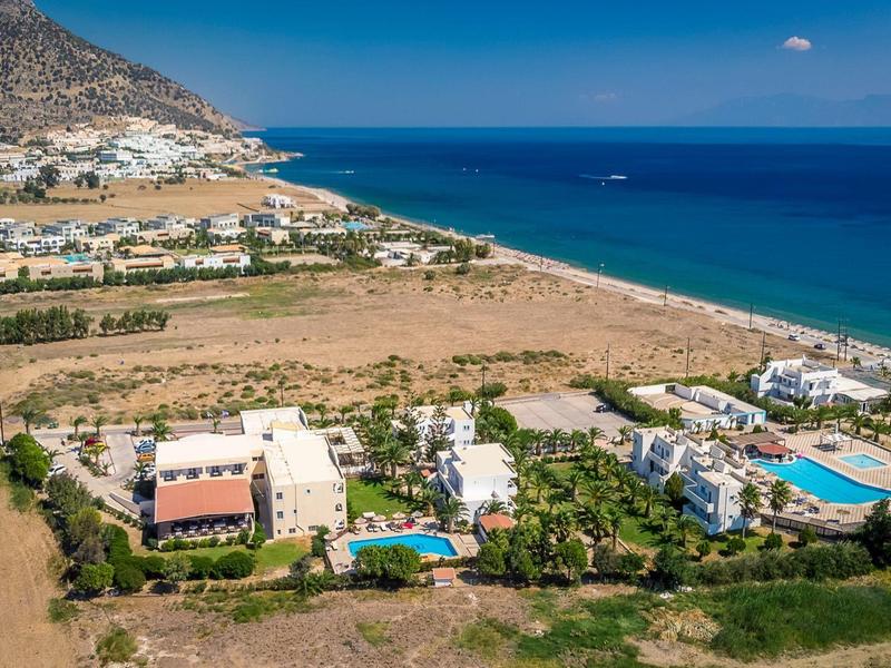 Küstenlandschaft mit Hotelanlagen, Pools, Strand und blauem Meer im Hintergrund unter klarem Himmel.