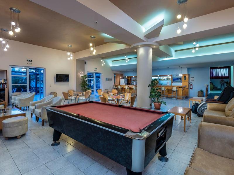 Großer, heller Raum mit rotem Billardtisch, Sofas, Stühlen und moderner Beleuchtung.