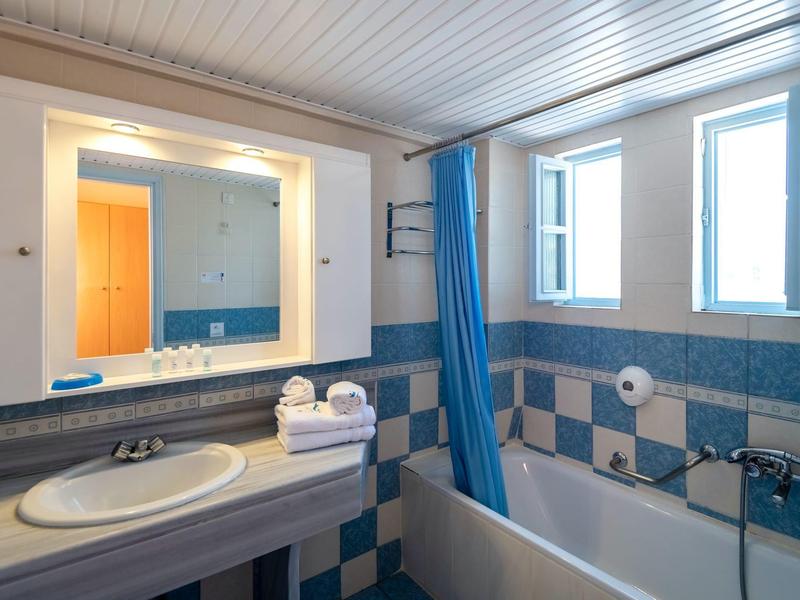 Helles Badezimmer mit blau-weißen Fliesen, Badewanne, Waschbecken und großem Spiegel.