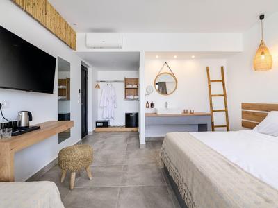 Chambre d'hôtel moderne avec grand lit, TV murale, coin salon et éléments décoratifs.