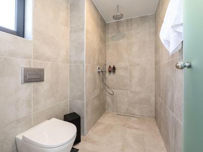 Espace douche de salle de bain moderne et lumineux avec carrelage beige et WC mural.