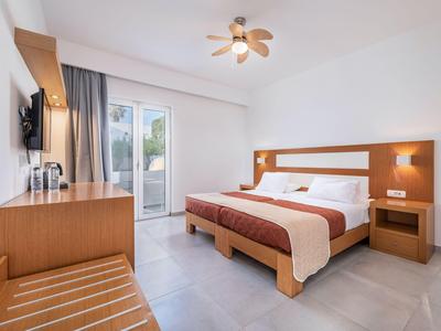 Chambre d'hôtel lumineuse avec lit double, mobilier en bois et accès au balcon à la lumière du jour.