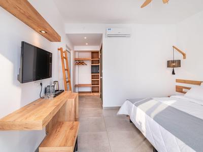 Chambre d'hôtel moderne avec lit double, TV murale et placard ouvert.