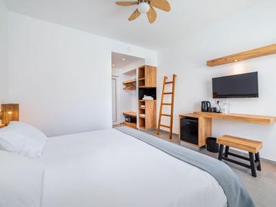 Chambre d'hôtel moderne avec literie blanche, télévision murale et accents en bois.