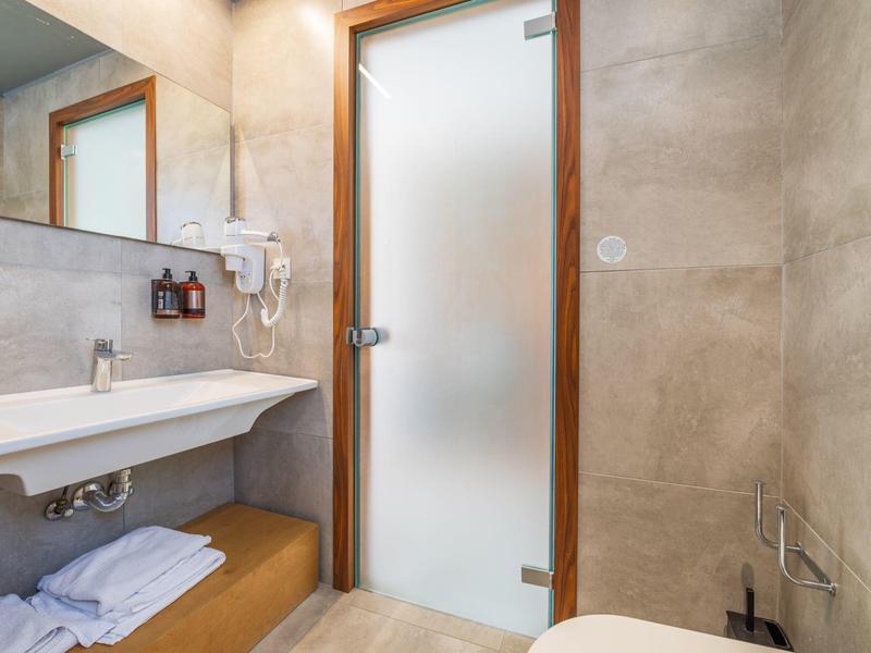 Bagno moderno con lavabo, specchio, asciugamani e porta in vetro satinato.