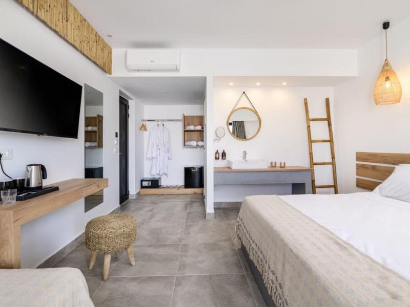 Camera d'hotel luminosa e moderna con letto grande, TV e arredamento minimalista.