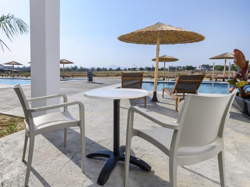 Due sedie e un tavolo su una veranda con vista su una piscina e il mare.