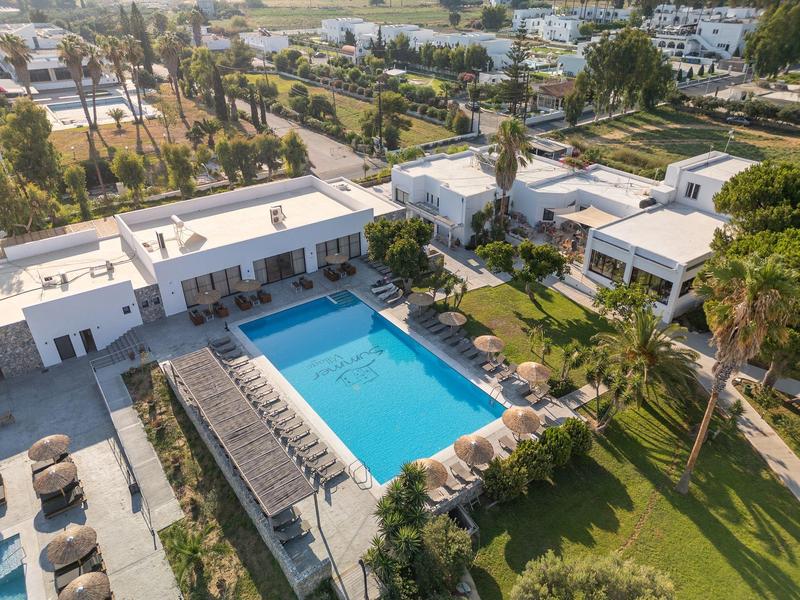 Complesso alberghiero moderno con piscina all'aperto, lettini e palme verdi in un ambiente soleggiato.