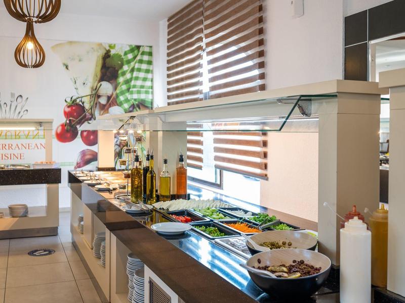 Buffet con vari piatti e oli in una stanza moderna e luminosa con tende a veneziana.