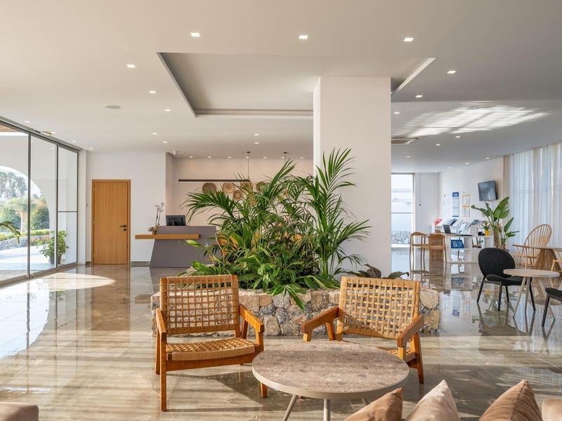 Area lounge moderna dell'hotel con posti a sedere, piante e grandi finestre.