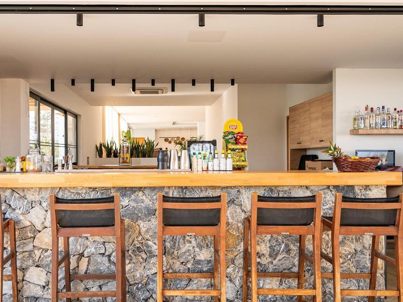 Area bar di un hotel moderno con sedie in legno, muro in pietra e arredamento minimalista.