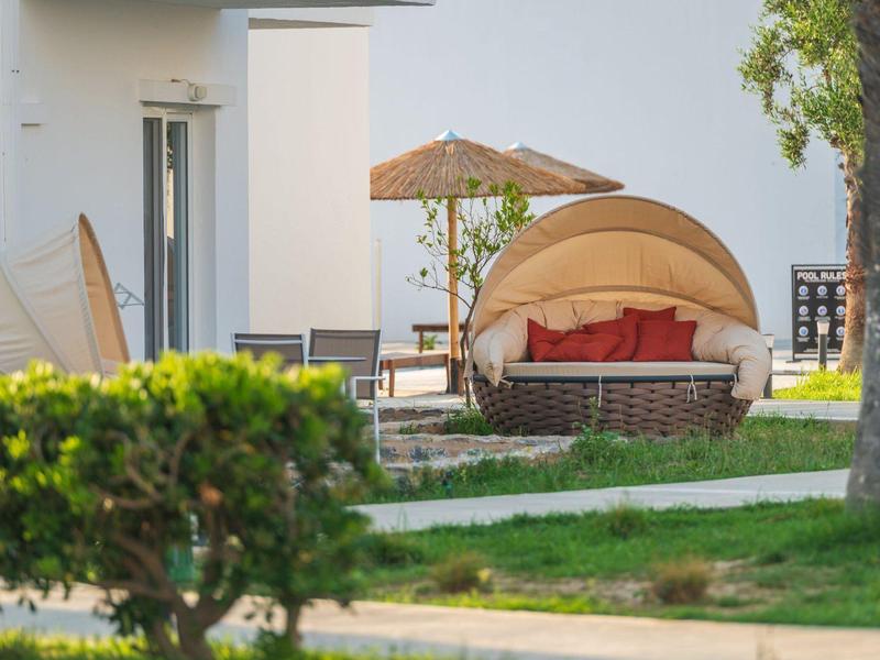 Sedia da giardino rotonda confortevole con ombrellone su prato dell'hotel.