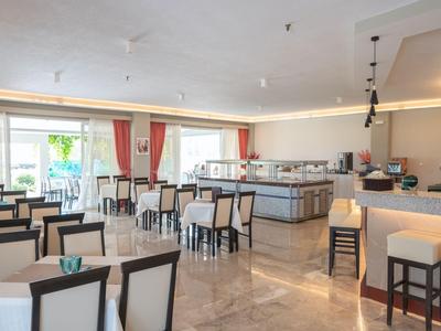 Ristorante luminoso e moderno con sedie imbottite e grandi finestre con vista sulla terrazza.