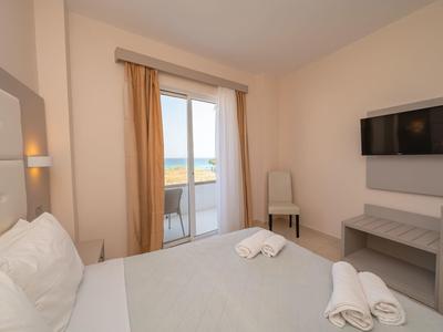 Camera d'hotel moderna con letto matrimoniale, TV a parete e balcone con vista sul mare.
