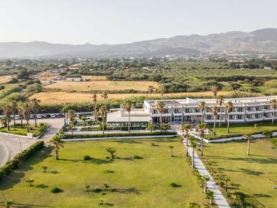 Ampio hotel con edifici moderni e prati verdi in un ambiente rurale con montagne sullo sfondo.