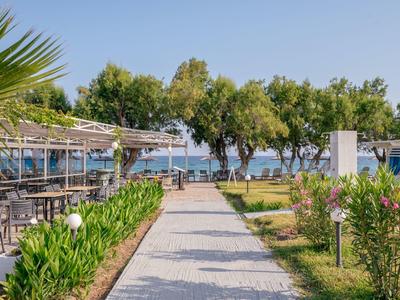 Ein Spazierweg mit Sitzgelegenheiten und Bäumen entlang des Wassers unter klarem Himmel.