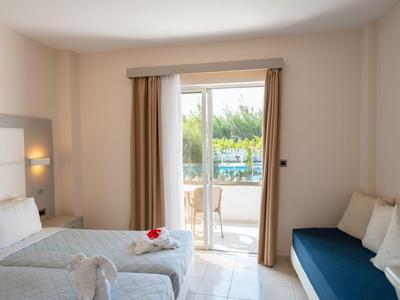 Camera d'hotel luminosa con due letti, balcone e sedute blu