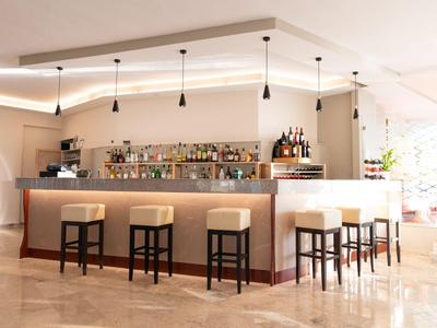 Bar dell'hotel moderna con bancone chiaro e sgabelli in una stanza elegante e ben illuminata.