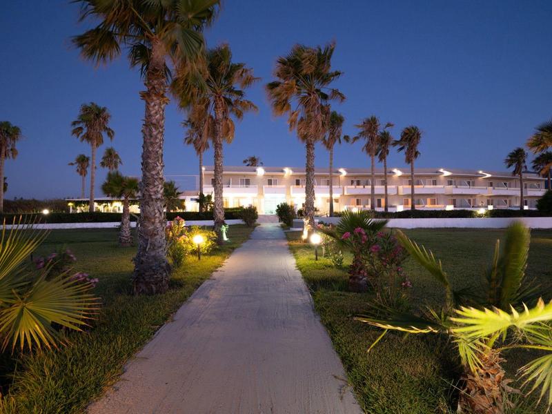 Sentiero illuminato con palme conduce a un moderno edificio di hotel di notte.