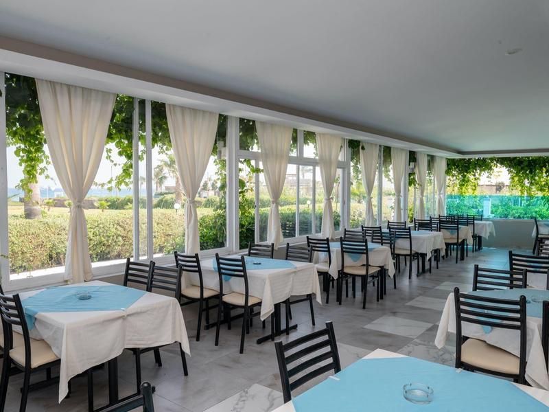 Sala da pranzo aperta con tavoli e sedie in un hotel con vista sul verde.