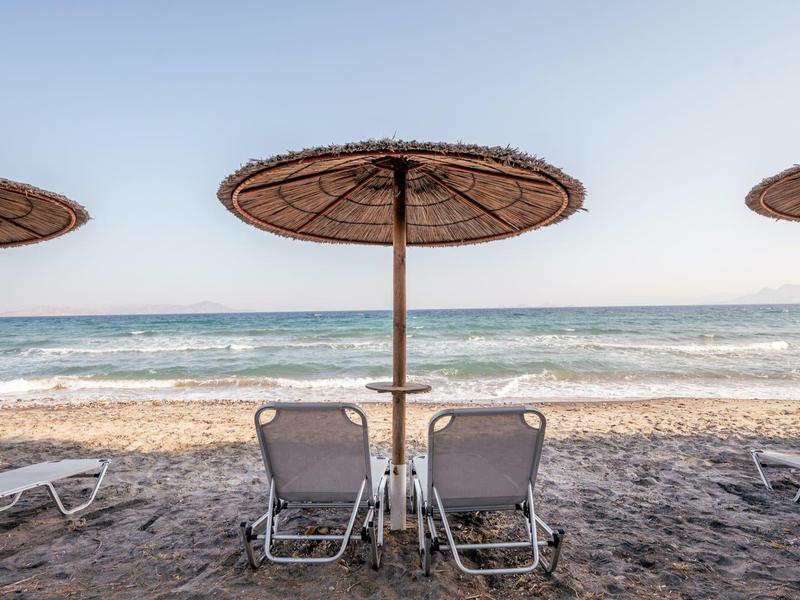 Due sdraio sotto un ombrellone sulla spiaggia sabbiosa con vista sul mare.