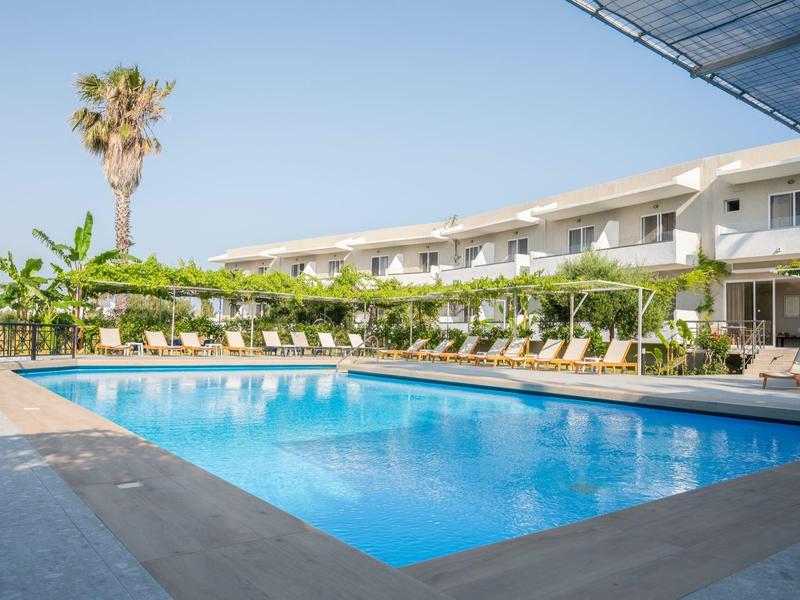 Hotel con grande piscina, lettini e piante sotto un cielo sereno