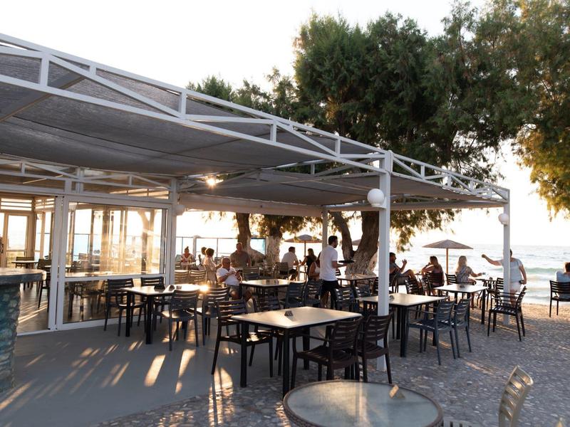 Caffè all'aperto con tavoli e sedie vicino al mare al tramonto