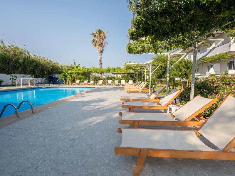 Area piscina con lettini e ombrelloni in un hotel sotto un cielo limpido.