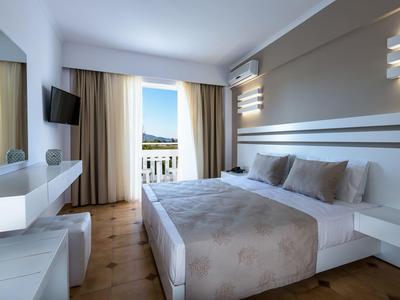 Modern eingerichtetes Schlafzimmer mit großem Bett, TV, Balkon und natürlichem Licht.