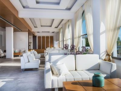 Bright hotel lounge area with white sofas, large windows, and elegant decor.