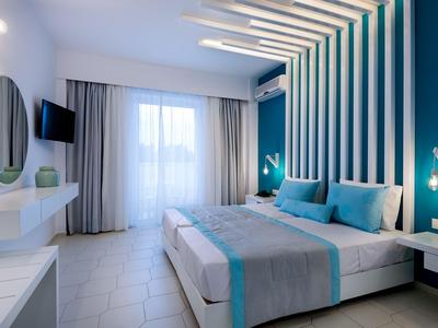 Modern hotel room with double bed, accent wall, and natural light from large window.