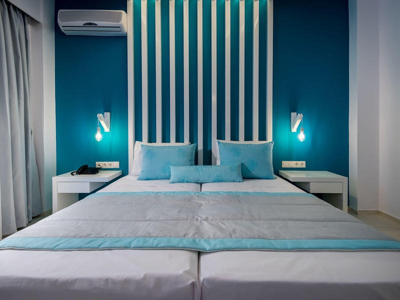 Nowoczesny pokój hotelowy z podwójnym łóżkiem w niebiesko-białych odcieniach i stolikami nocnymi