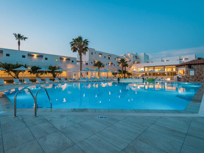 Oświetlony basen hotelowy z palmami i miejscami do siedzenia o zmierzchu