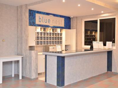 Moderner Empfangstresen mit grauer Oberfläche, blauem Dekor und Schild „blue nest“ in hellem Raum.