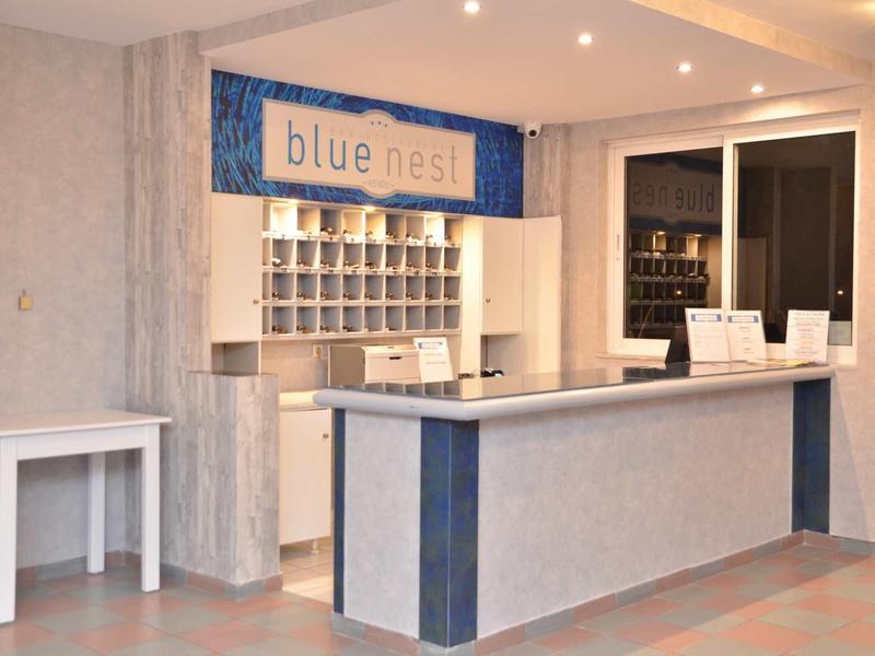 Moderní hotelová lobby s recepčním pultem a nápisem 'blue nest'.