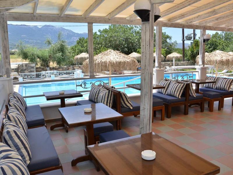 Zastřešená posezení s stolky a židlemi vedle bazénu v rekreačním areálu.