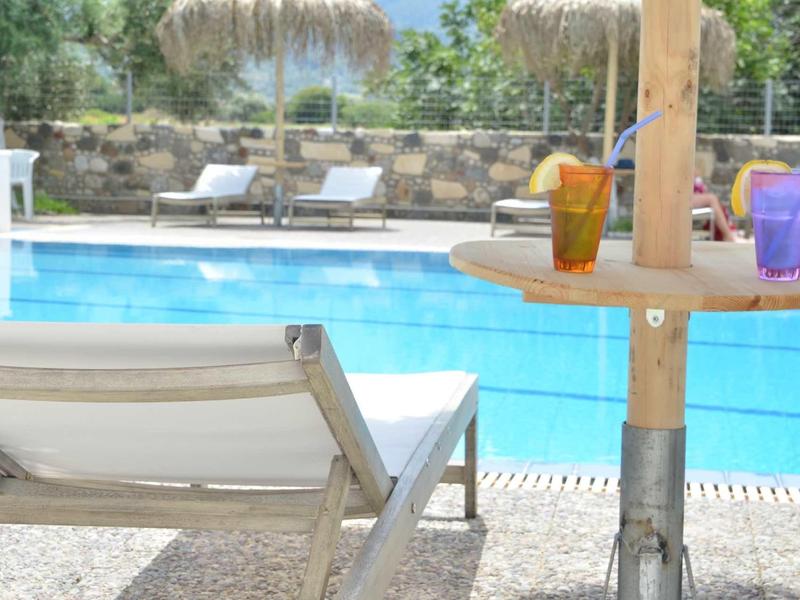 Dvě lehátka u bazénu s malým stolkem a nápoji ve slunné venkovní oblasti.